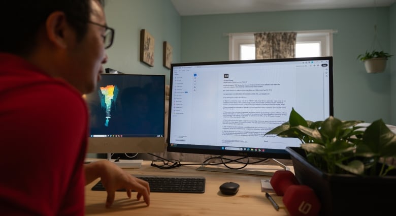 Un homme d’Asie de l’Est vêtu d’une chemise rouge est assis devant son ordinateur de bureau.  Il regarde un NDA sur l'écran que la Banque TD lui a envoyé par courriel. 